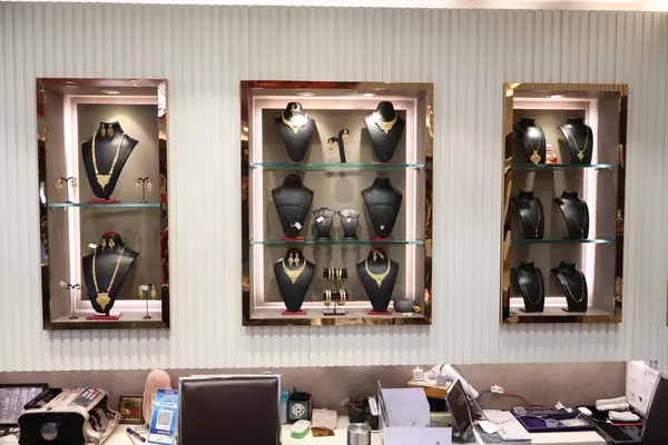 Gold necklace sets and earrings on bust stands in lit wall niches at the New Ratna Kendra showroom