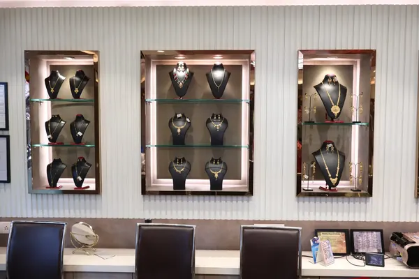 Gold necklaces and earrings displayed in glass-shelf niches above the sales counter